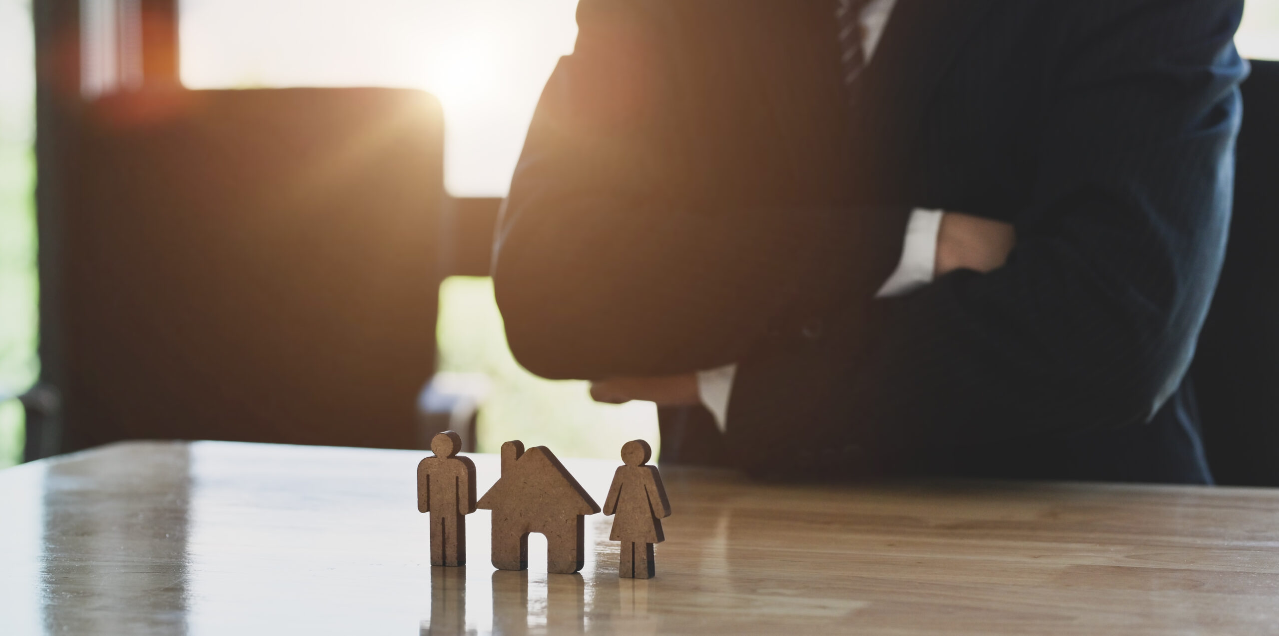 Young businessman looking at house and family models on the desk